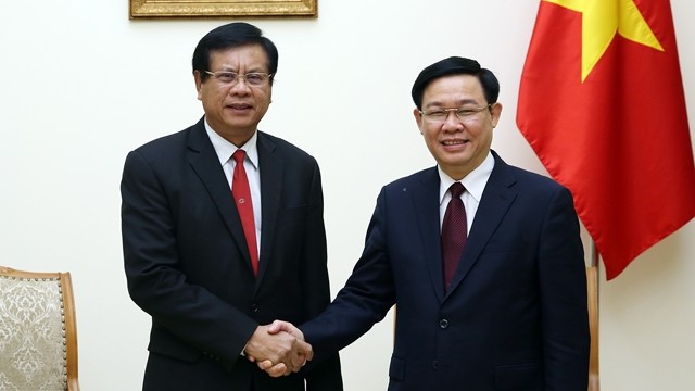 越南政府副总理王廷惠与老挝前政府总理、老挝国家经济研究院院长波松·布帕万握手。