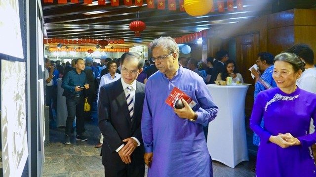 越南驻孟加拉国大使陈文科向孟加拉国文化部国务部长介绍参展图片。（图片来源：国际报）