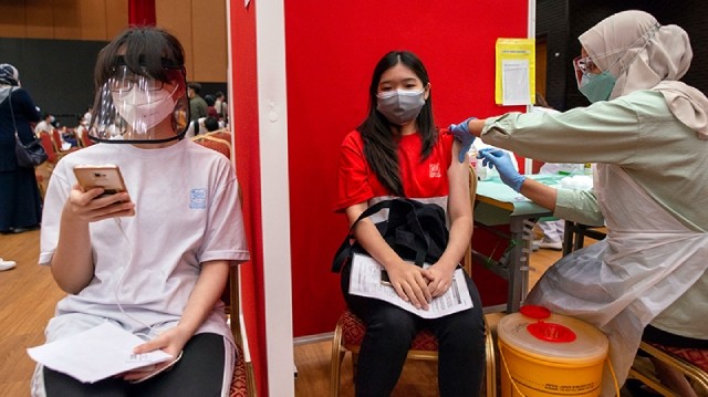 医疗人员在马来西亚吉隆坡为学生接种新冠疫苗。（图片来源：新华社）